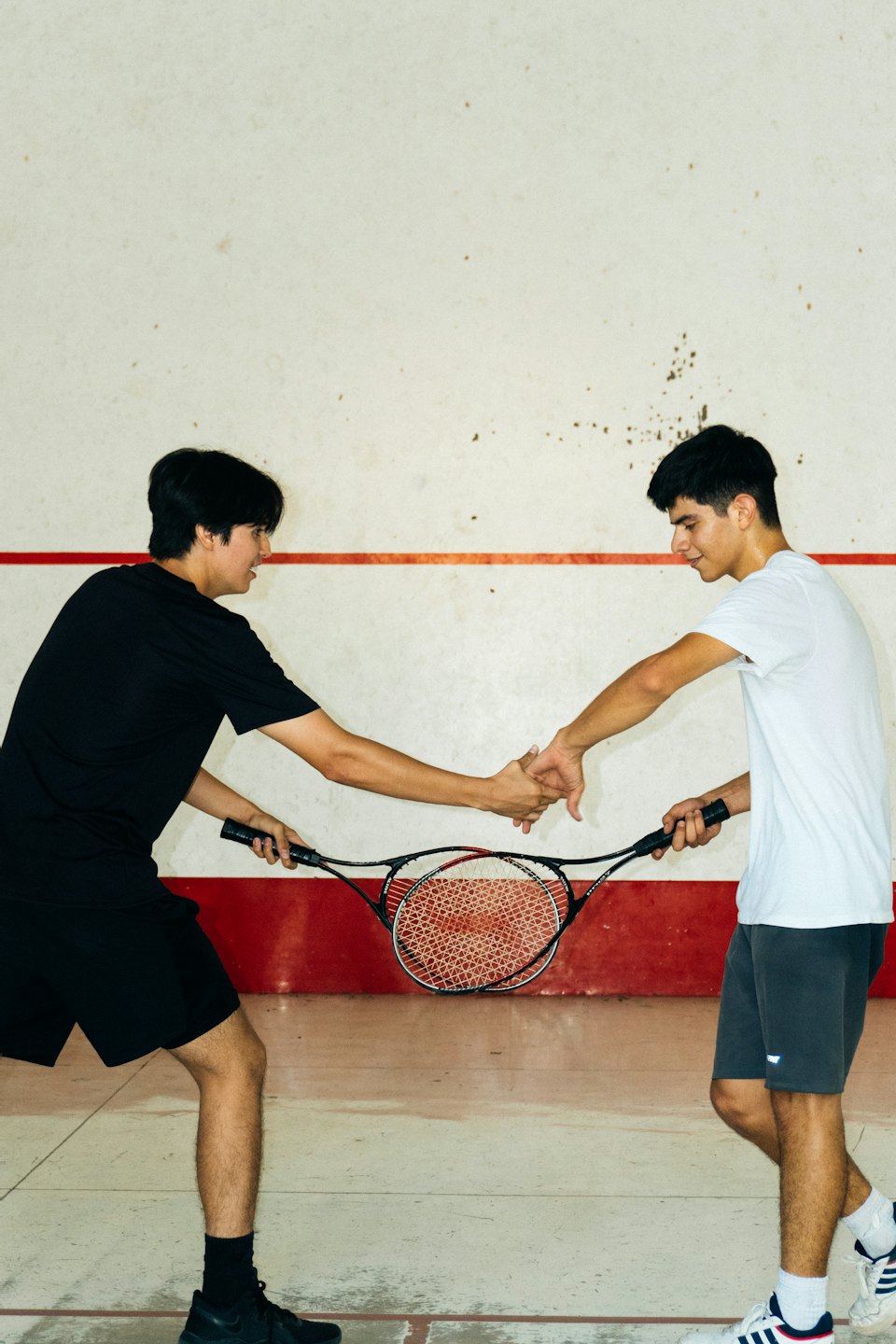Two squash players shake hands on the court.