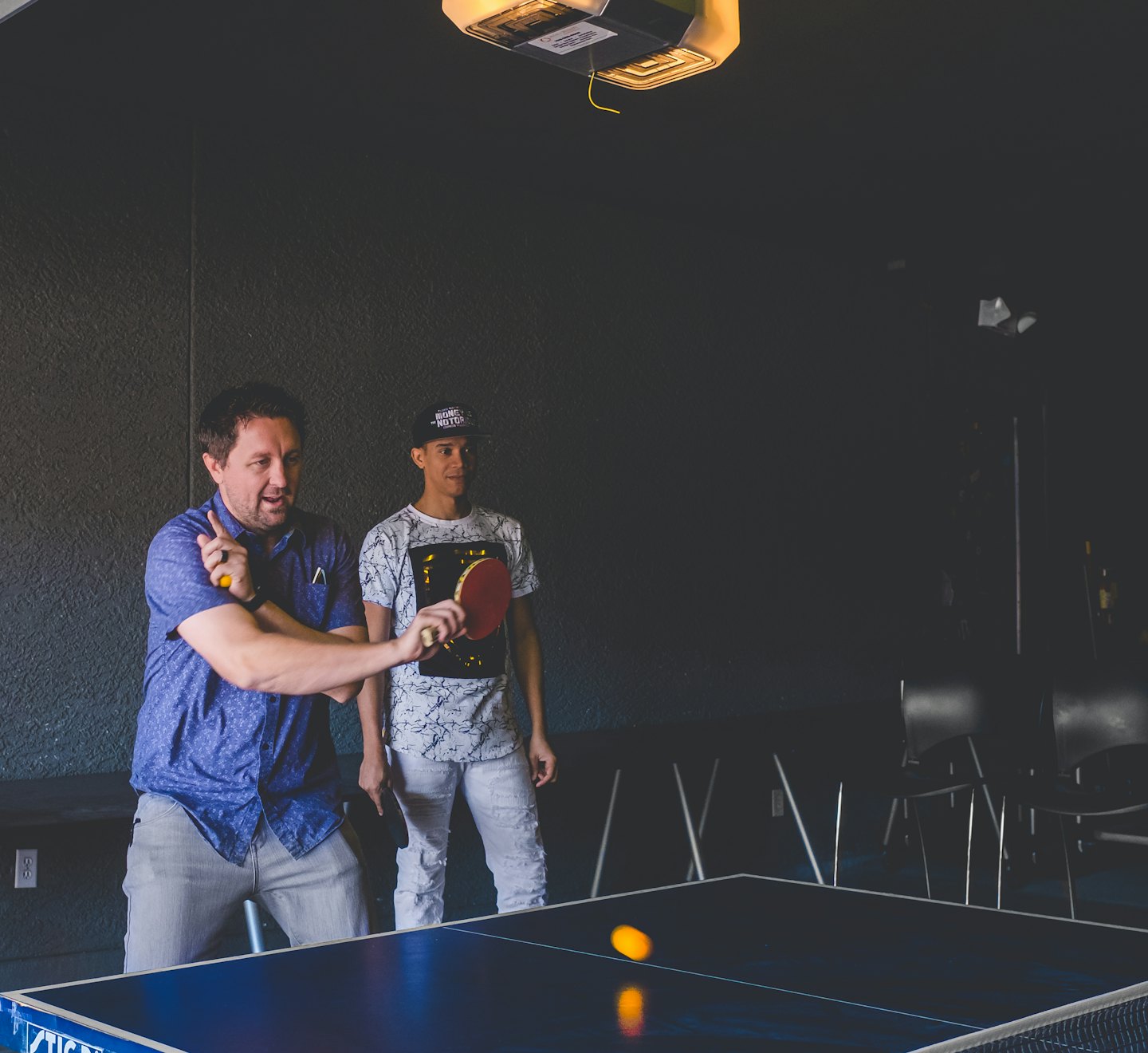 Two men playing table tennis in a recreational area.