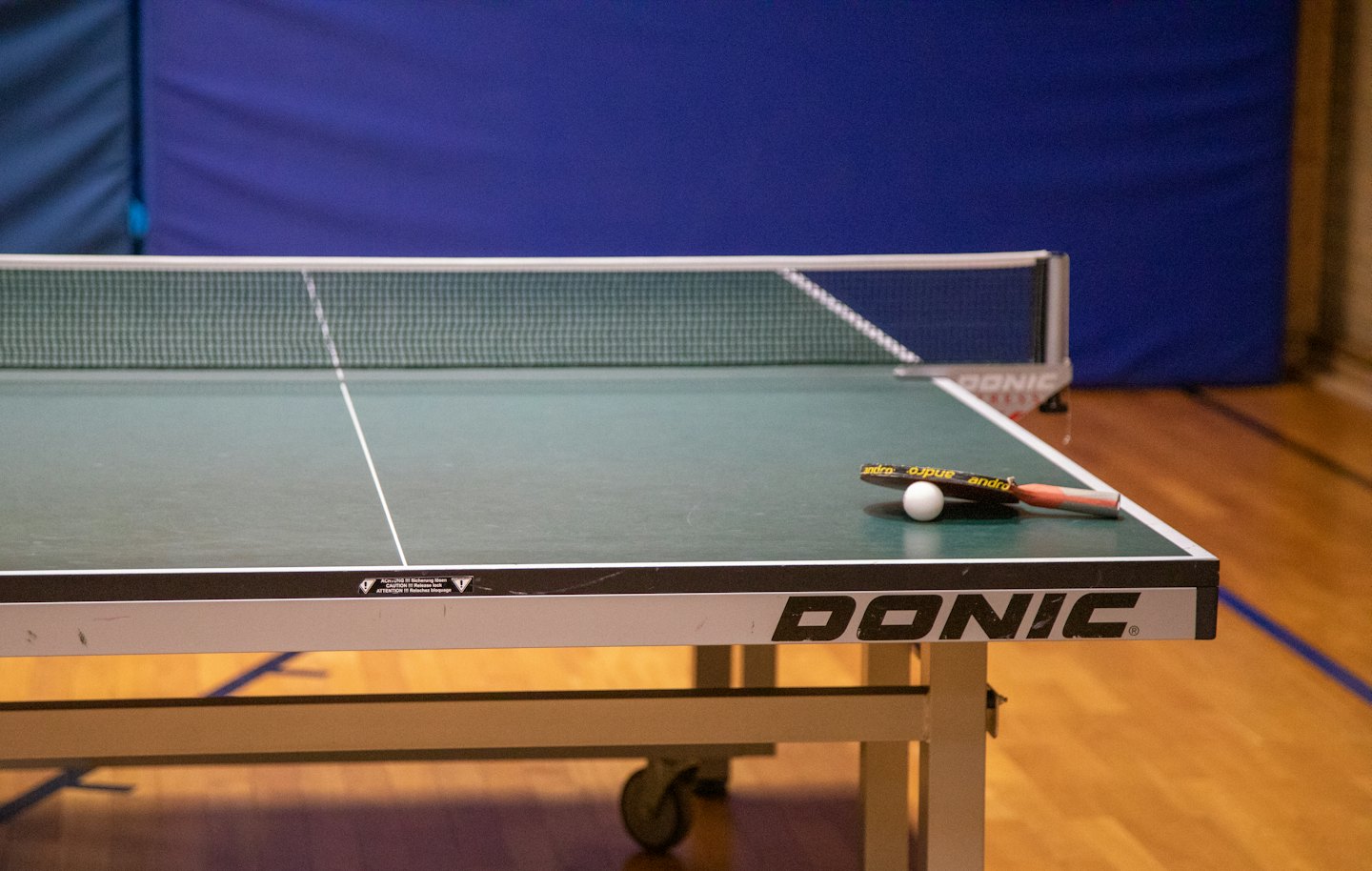 Green table tennis table with paddle and ball.